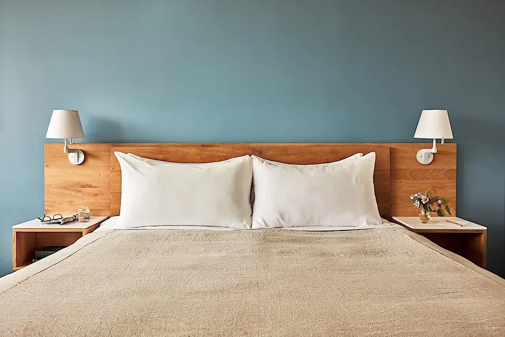 A guest room at The Study at Yale, with a wooden headboard, white bedding and reading lamps